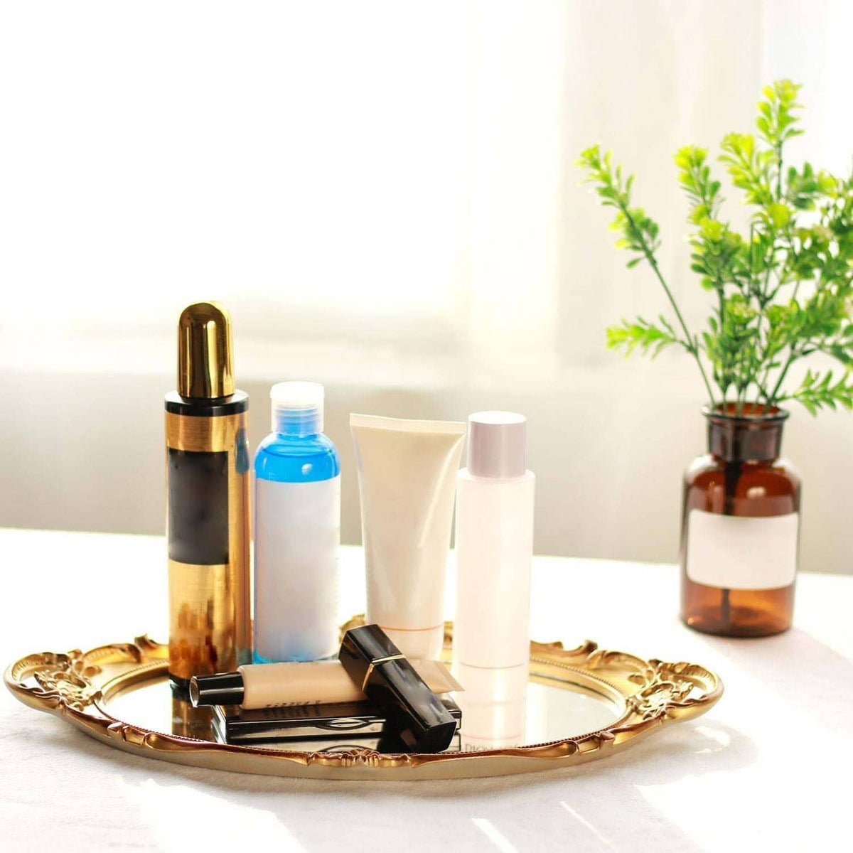 Gold oval decorative tray holding skincare bottles, tube, and spray container