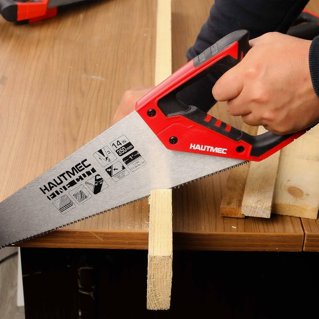 Hand holding a red-and-black hand saw cutting wood on a workbench