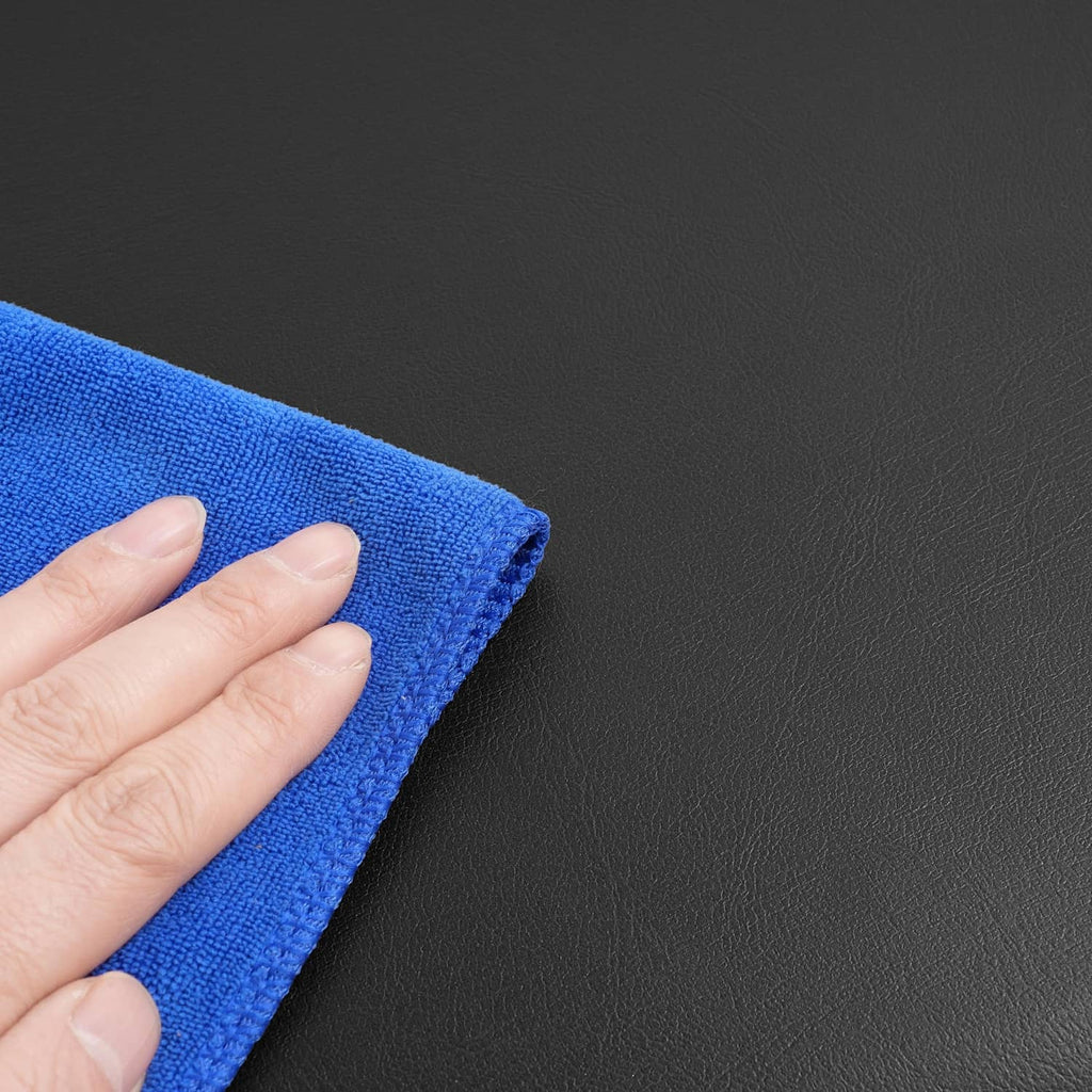 Blue microfiber cloth wiping black vinyl cushion surface corner