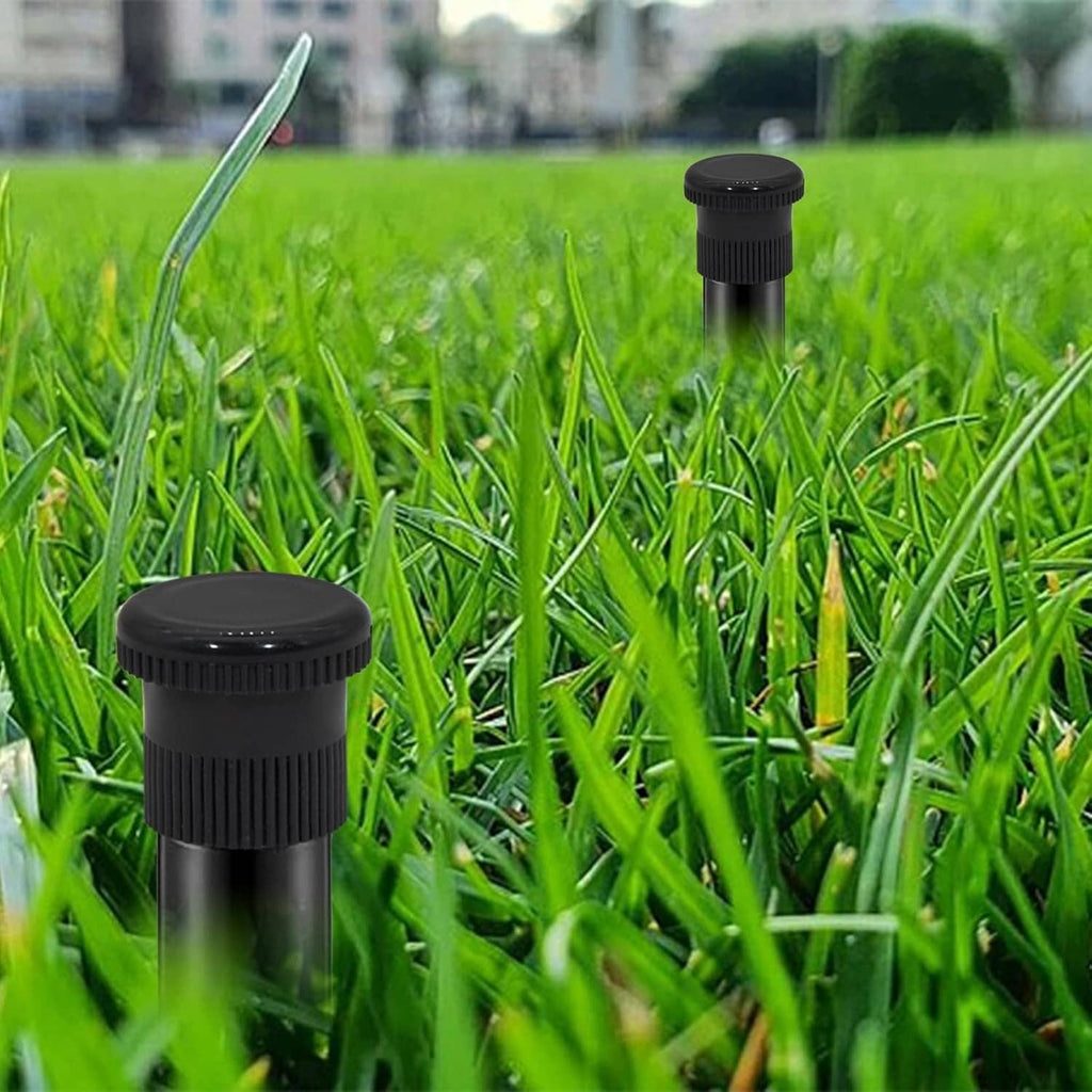 Black sprinkler shutoff nozzle rising from grass with nozzle cap