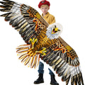 Brown and white eagle kite with orange chest, held by a child while flying