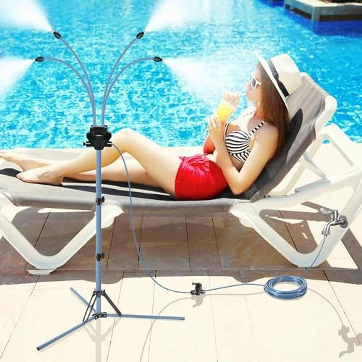 Tall standing misting tripod with blue nozzle heads and hose connected, used beside pool lounge
