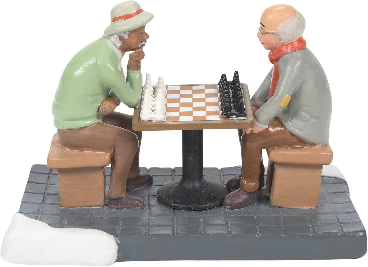 Chessboard figurine scene: two seated men in winter clothes at a table with a stone-like base.