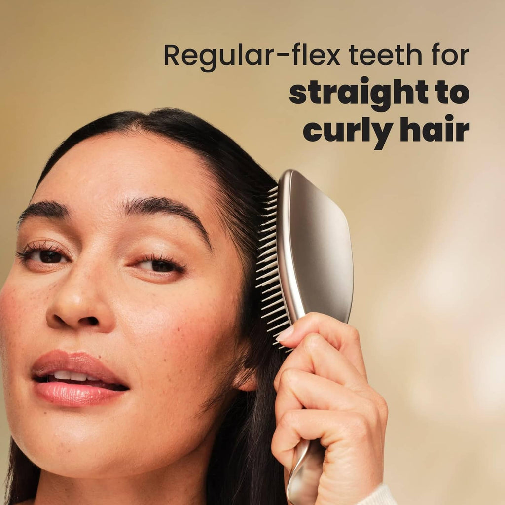 Champagne gold detangling hairbrush held near head, fine bristles visible