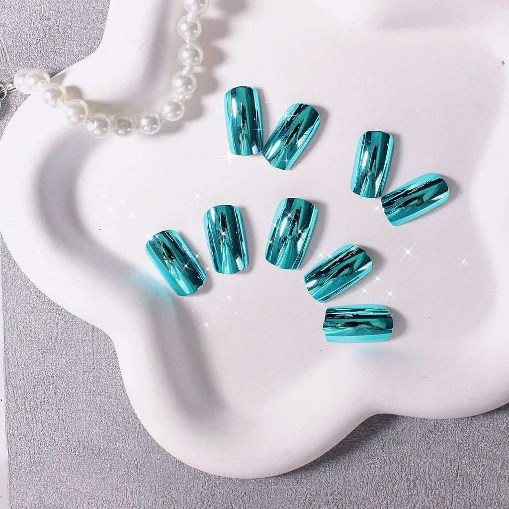 Teal blue chrome square press-on nails tips laid out on a white curved display.