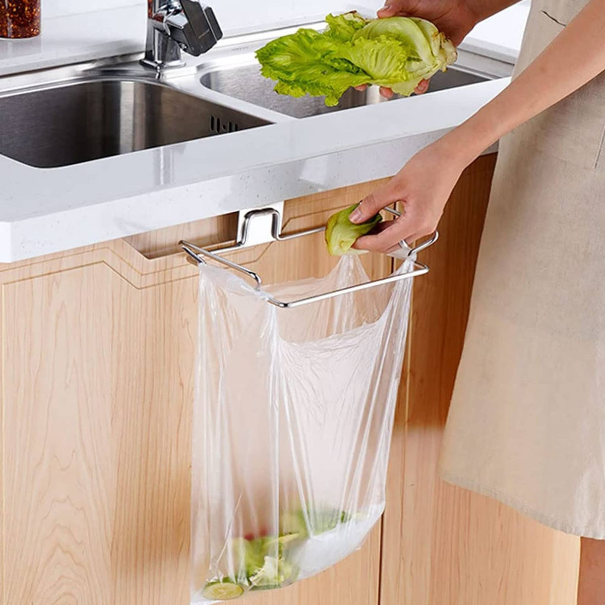 Stainless steel trash bag holder mounted under sink cabinet with bag attached