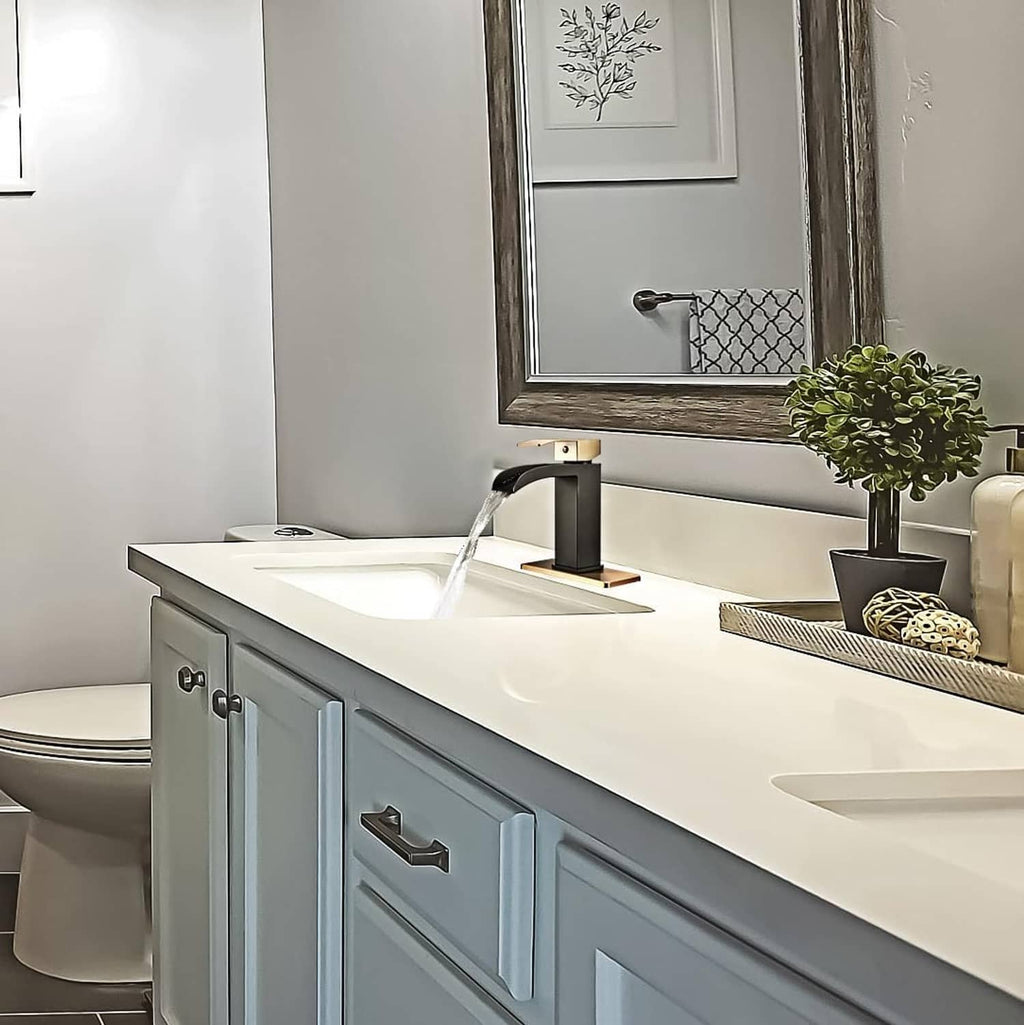 Black and gold single-handle waterfall bathroom faucet on vanity sink