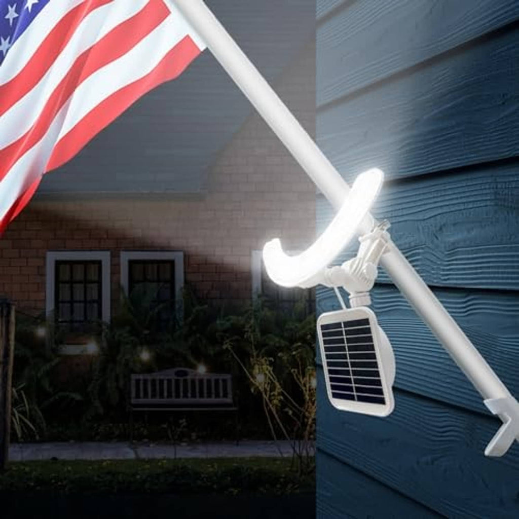 Solar flagpole light glowing on a white flagpole with rectangular solar panel