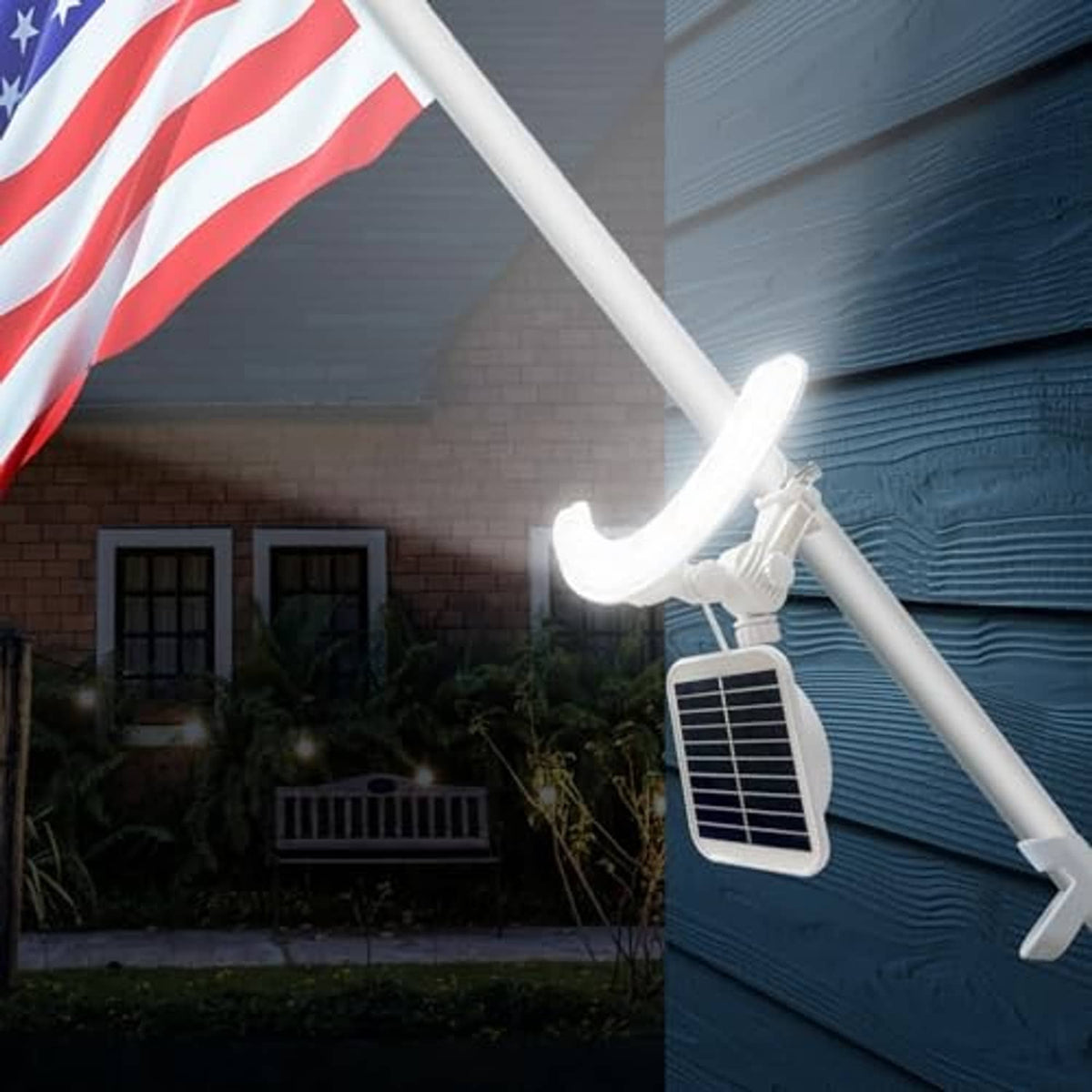 Solar flagpole light glowing on a white flagpole with rectangular solar panel