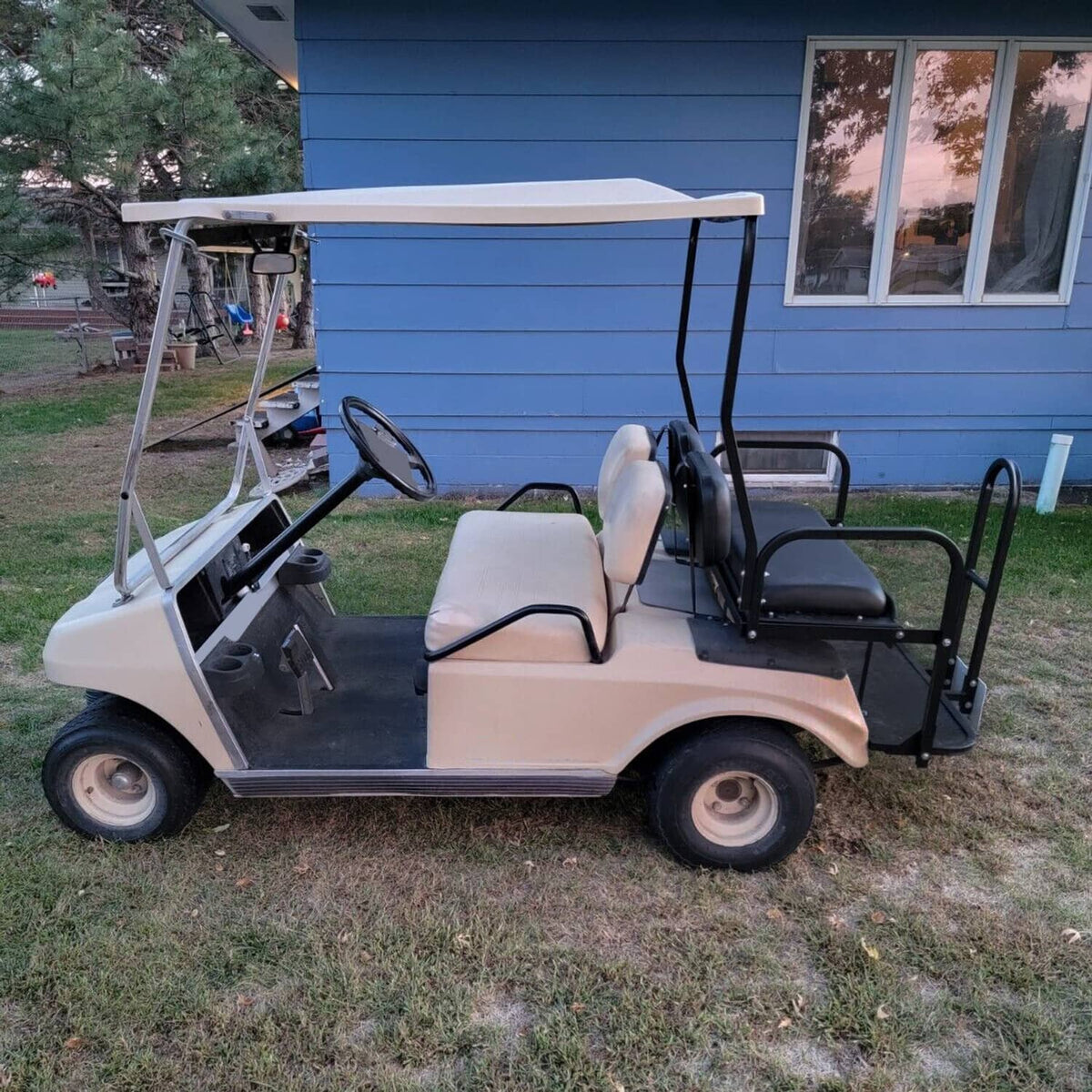 Golf cart with installed rear flip seat kit featuring black armrests and platform