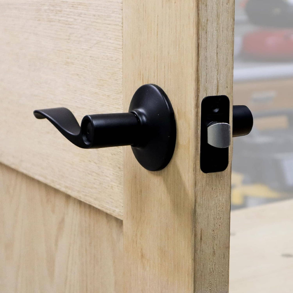 Black lever handle and door latch on a wooden door with rectangular strike plate