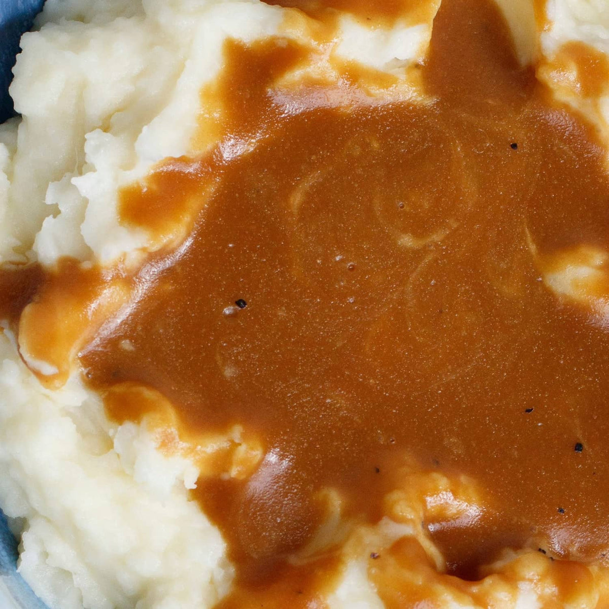 Brown gravy poured over mashed potatoes close-up