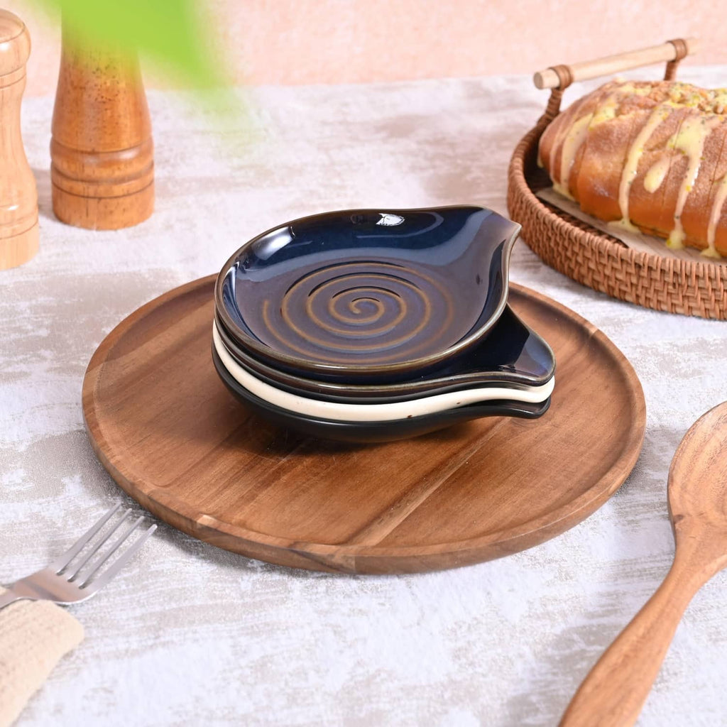 Dark blue ceramic spoon rest with spiral swirls on a round wooden tray