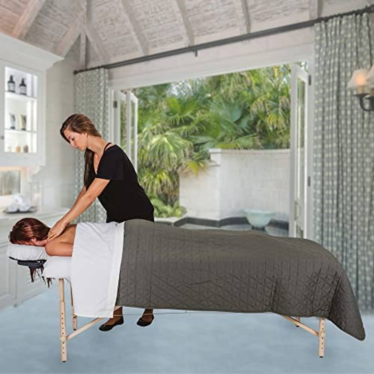 Quilted microfiber blanket draped over a bed in medium gray with square stitching