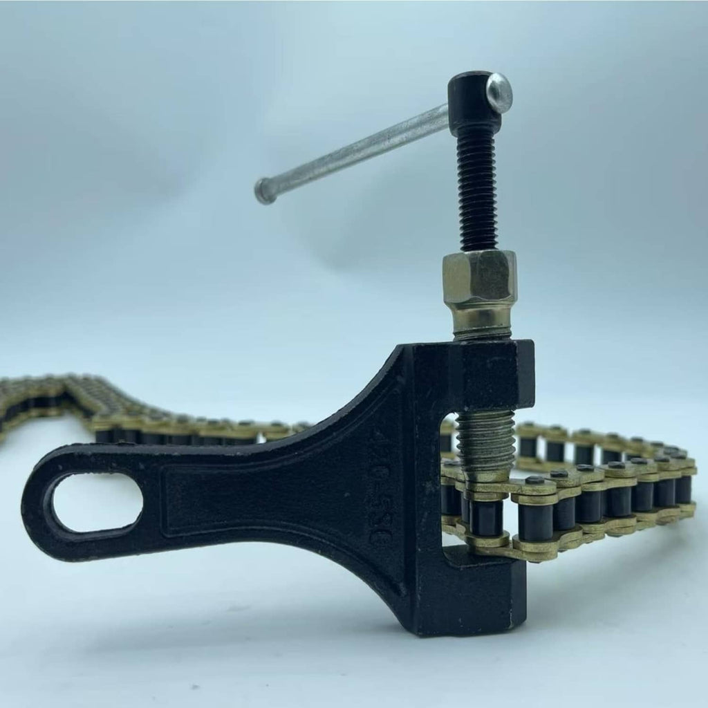 Black chain breaker plier clamp holding gold motorcycle roller chain