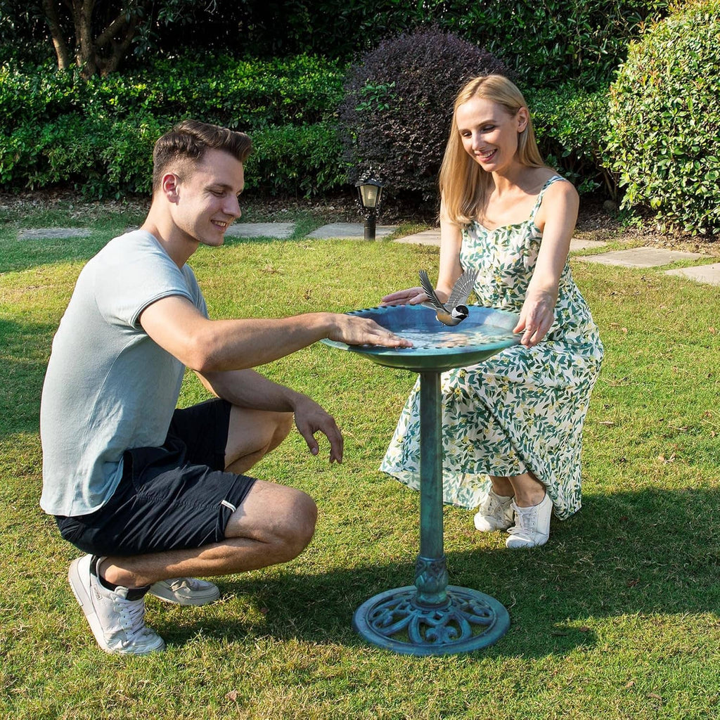Outdoor turquoise bird bath on pedestal stand with water basin, viewed at lawn level
