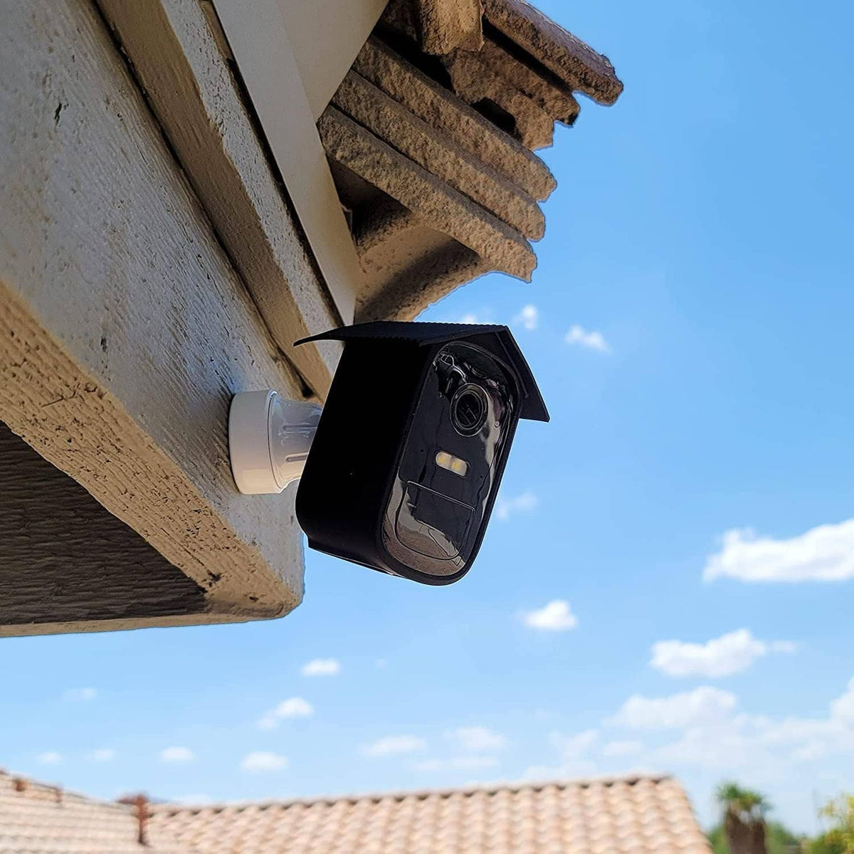 Black silicone camera cover mounted under eave, open lens window