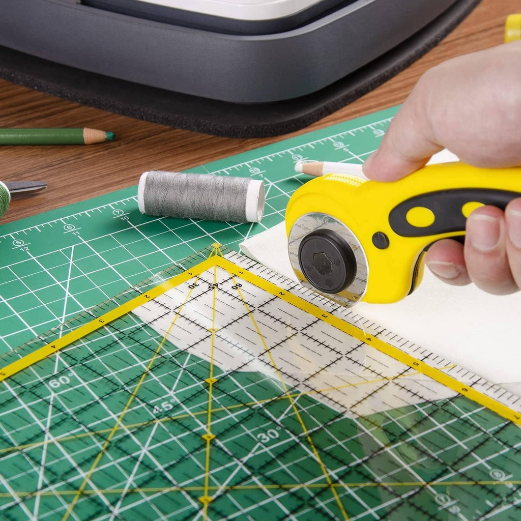 Green cutting mat grid with yellow-and-black rotary tool cutting along marked lines