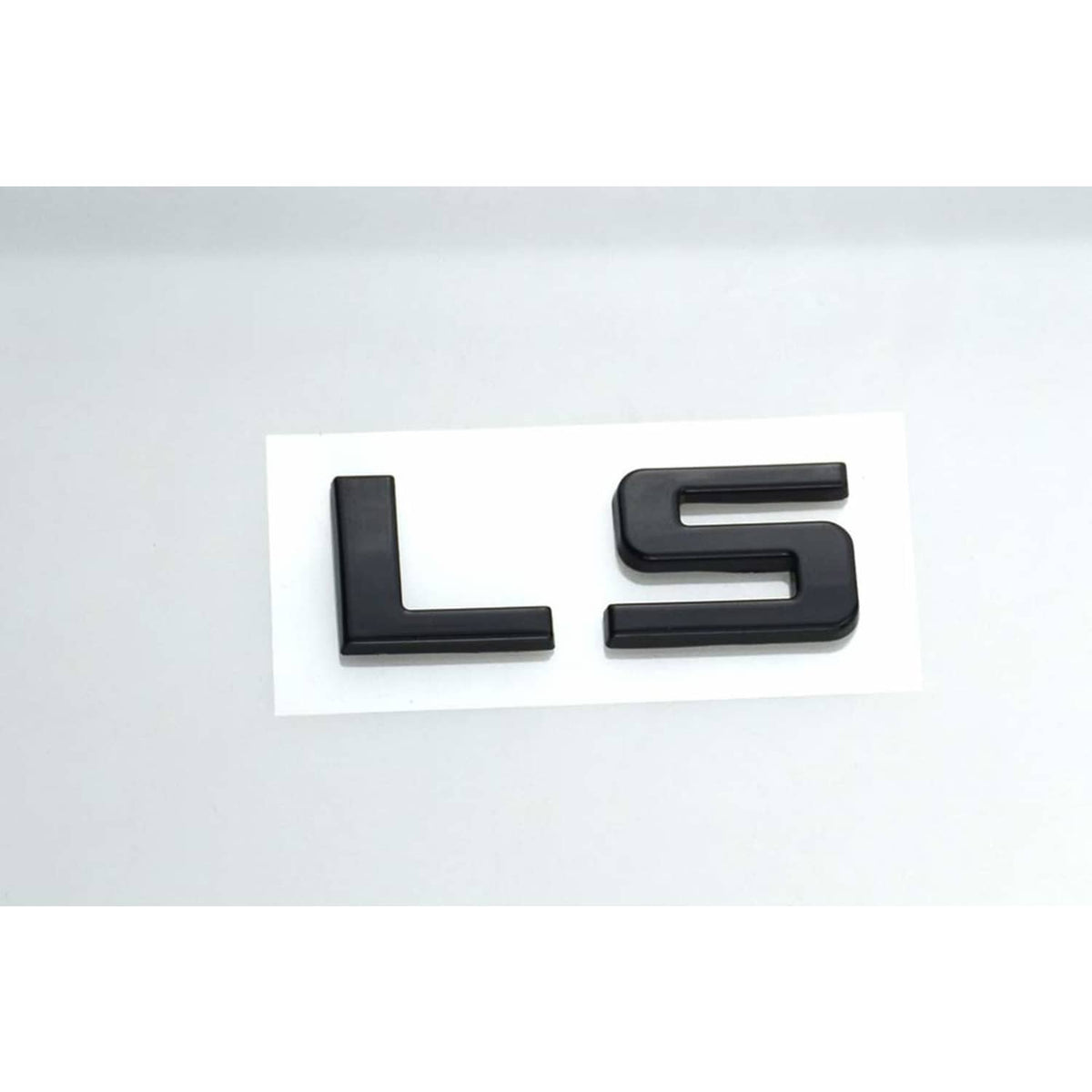Gloss black LS emblem letters, two-piece badge set on white backing.