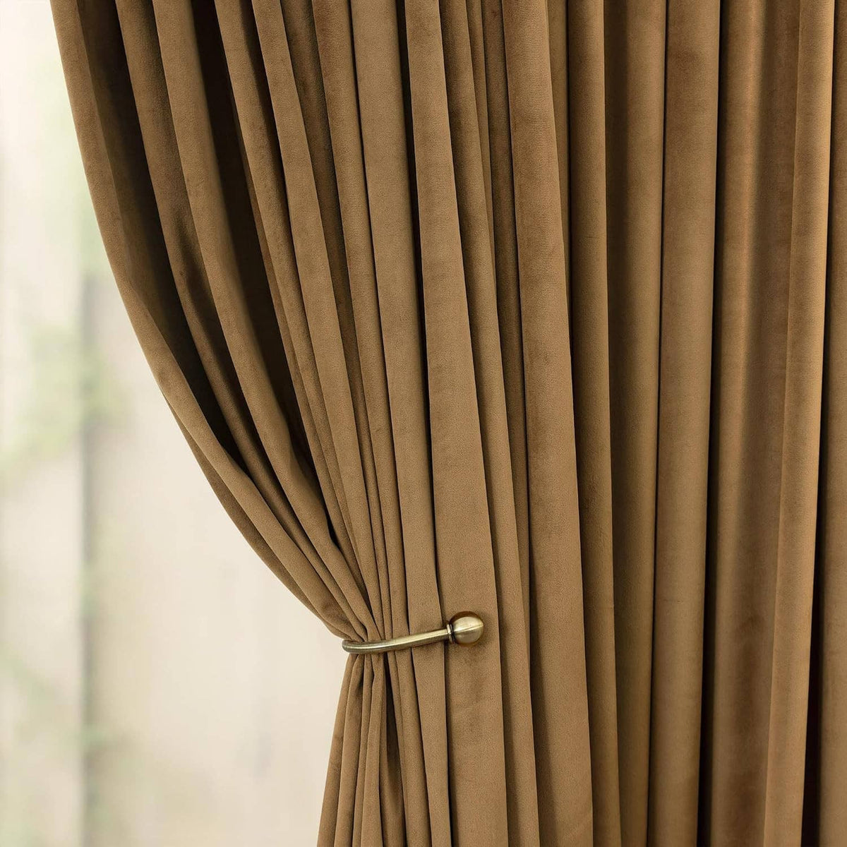 Gold brown velvet curtains with tieback holding fabric to the side.