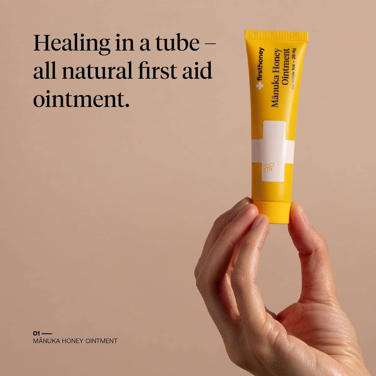 firsthoney manuka honey ointment yellow tube held in hand, applicator opening visible
