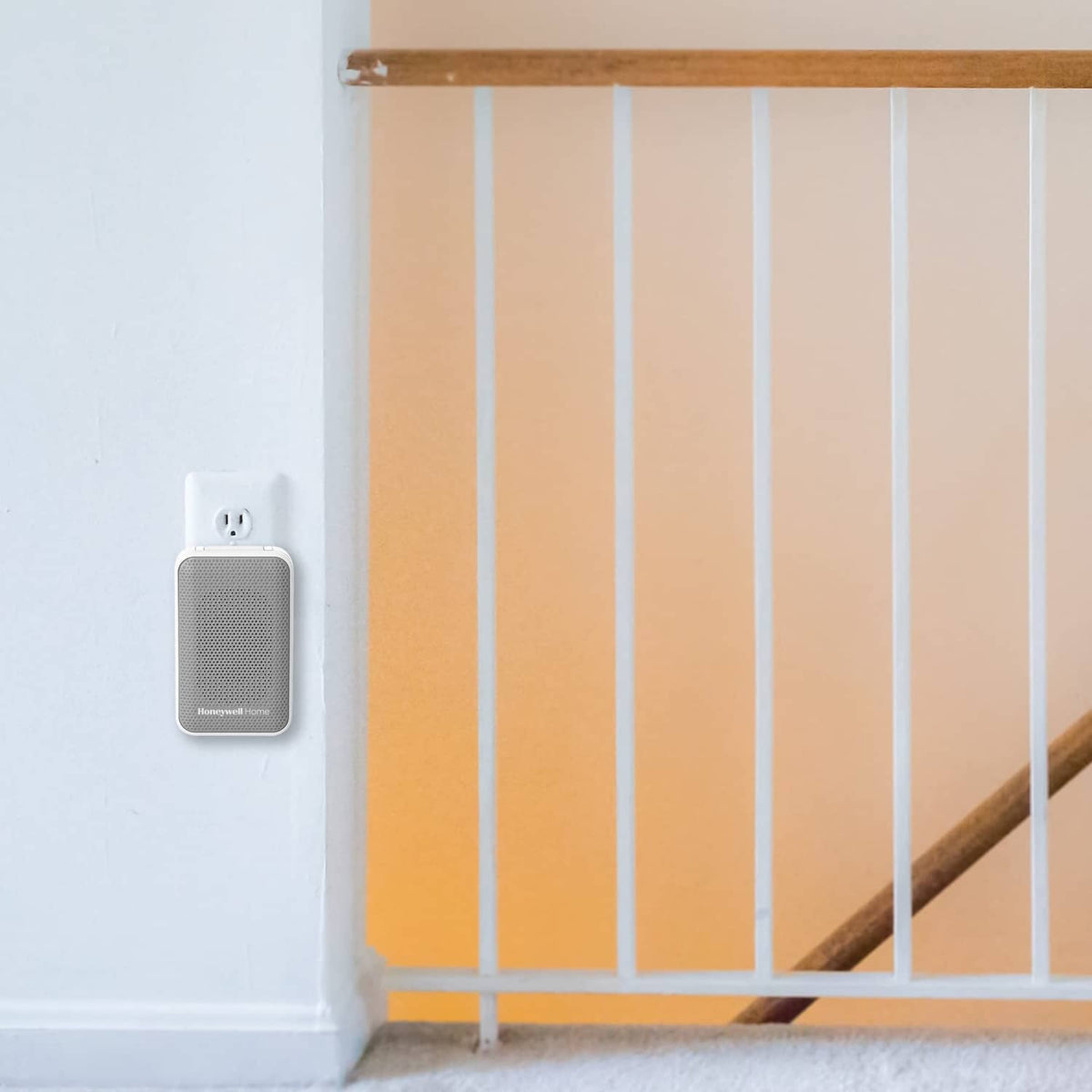 Small white wireless doorbell button mounted on wall near door railing