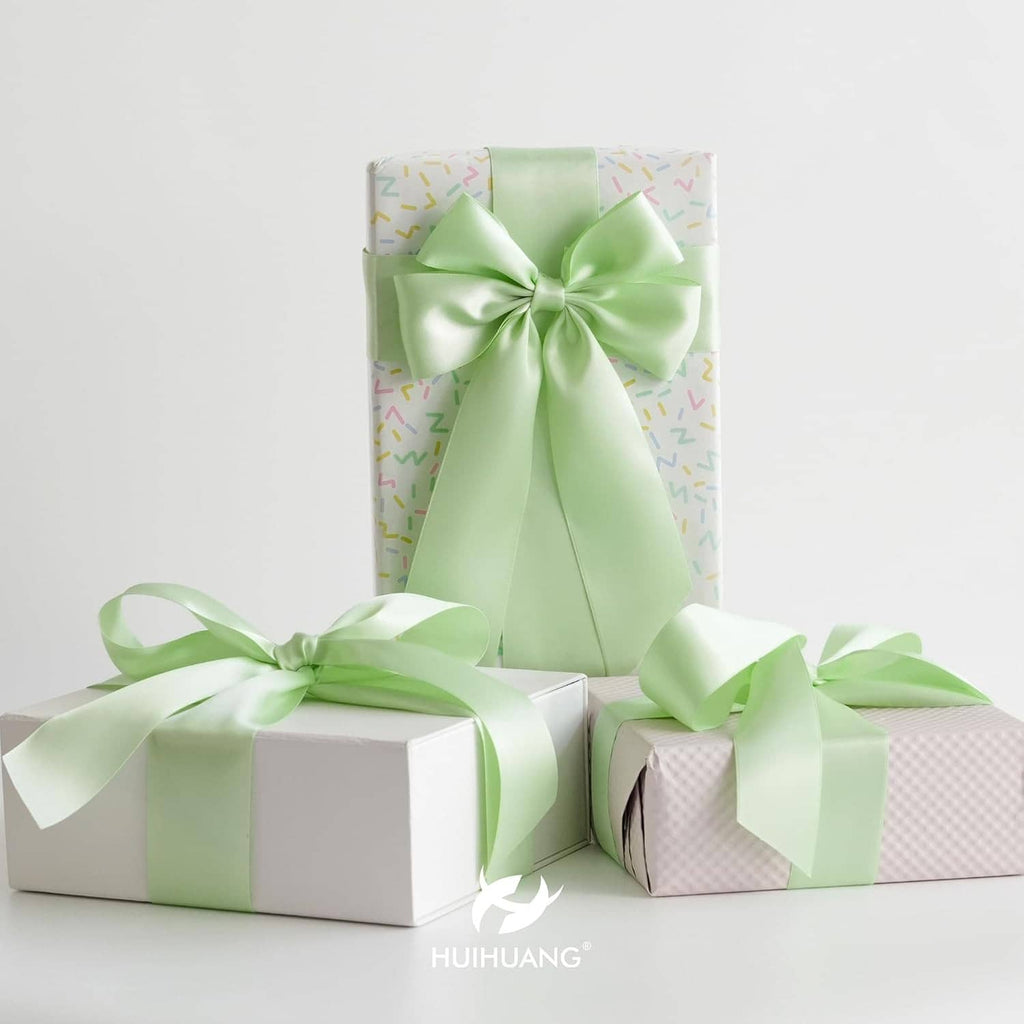 Seafoam green satin gift wrap ribbon bow on wrapped boxes with layered ribbon tails.