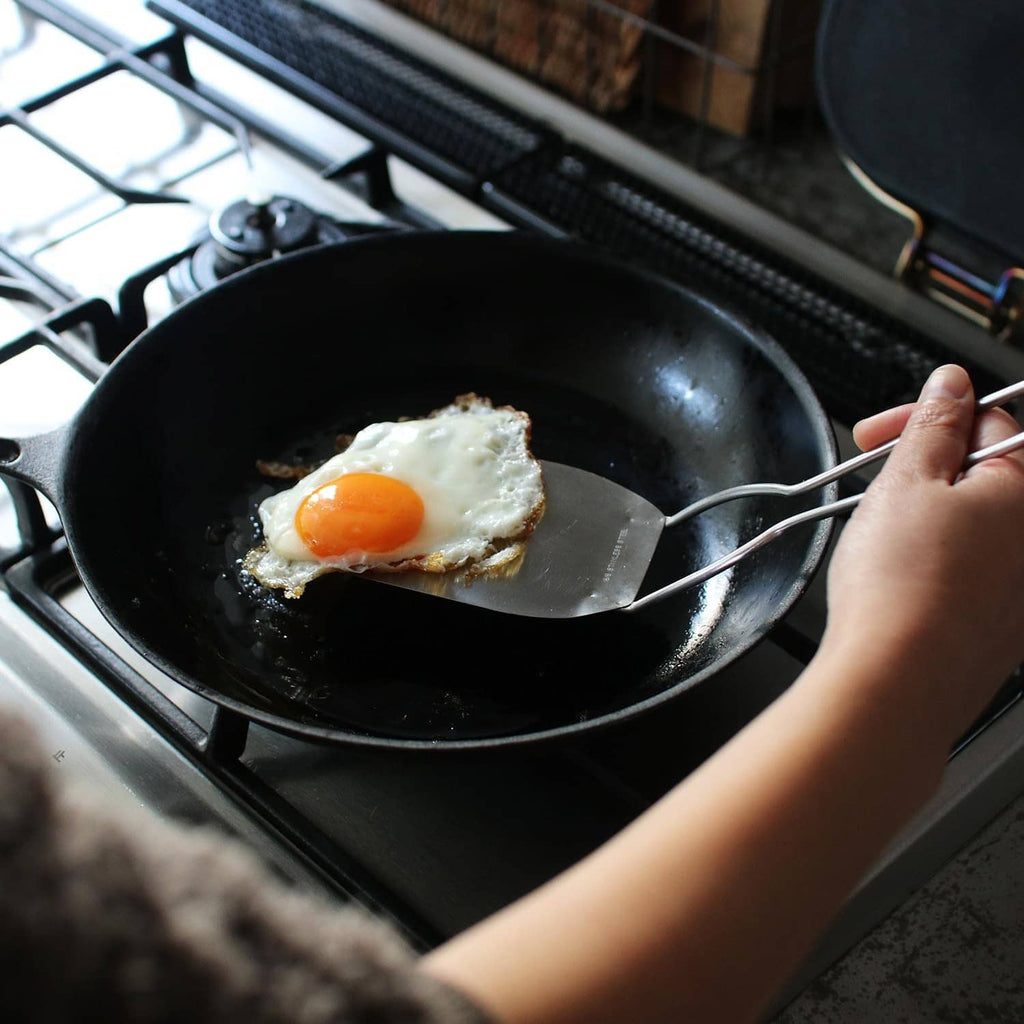 Stainless steel spatula lifting a fried egg from a skillet