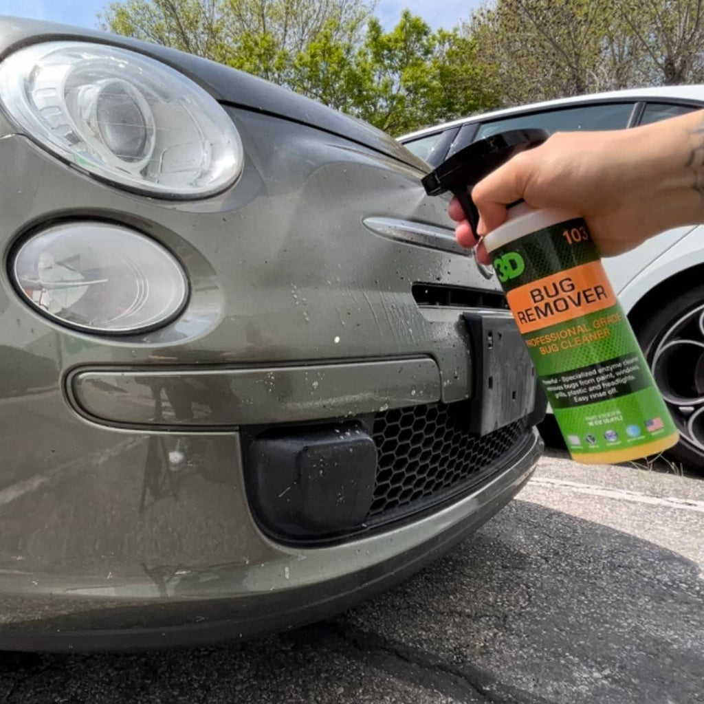 Hand spraying 3D bug remover cleaner on a car grille; bottle with green label