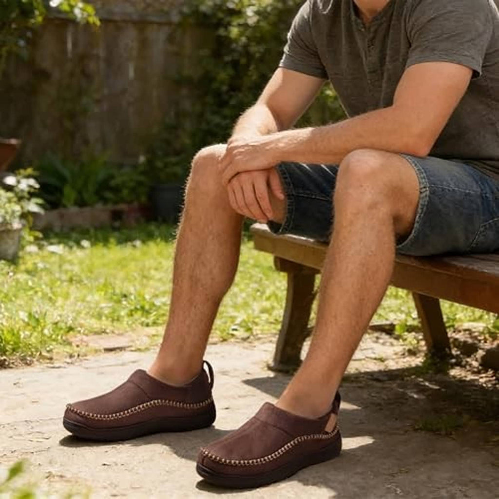 Brown men’s moccasin slippers worn outdoors, showing stitched toe and dark rubber sole