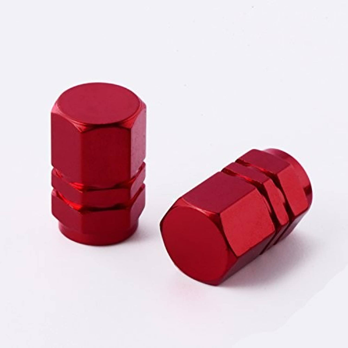 Two red tire valve stem caps with hex top and ridged bands over threaded openings