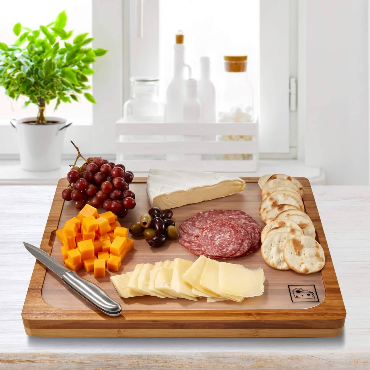 Bamboo serving tray with cheese slices, salami, grapes, and crackers