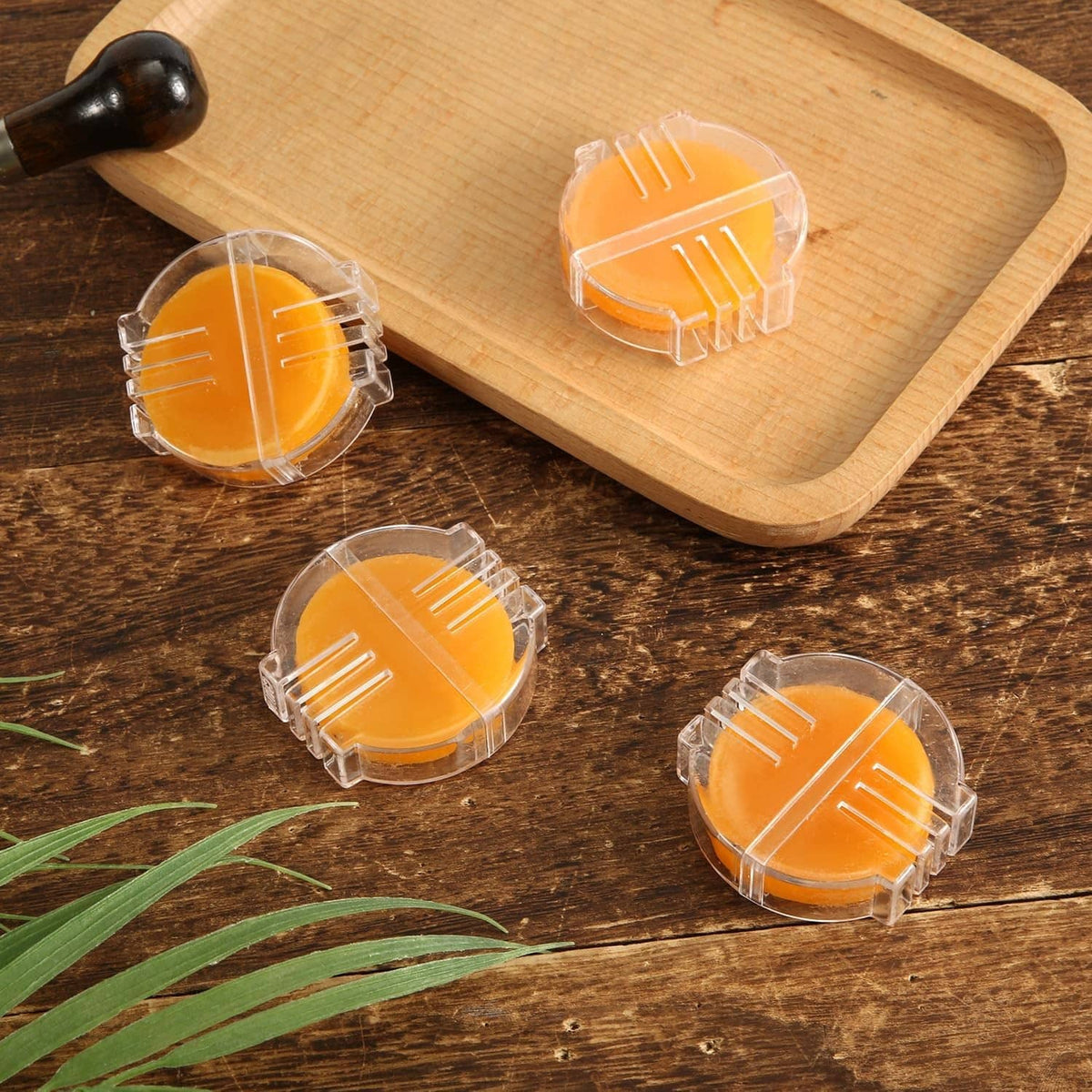Set of four orange beeswax thread conditioner discs in clear plastic holders