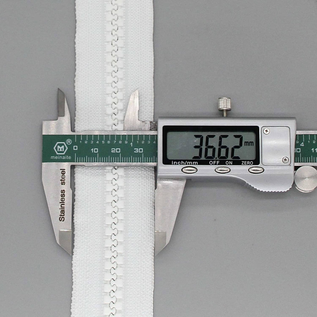 White separating zipper measured with a digital caliper, showing length in mm