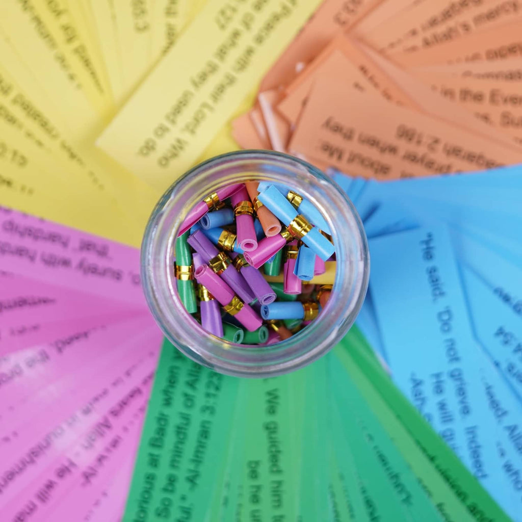 Close-up of Quran verses jar mouth with gold-topped colorful capsule rolls