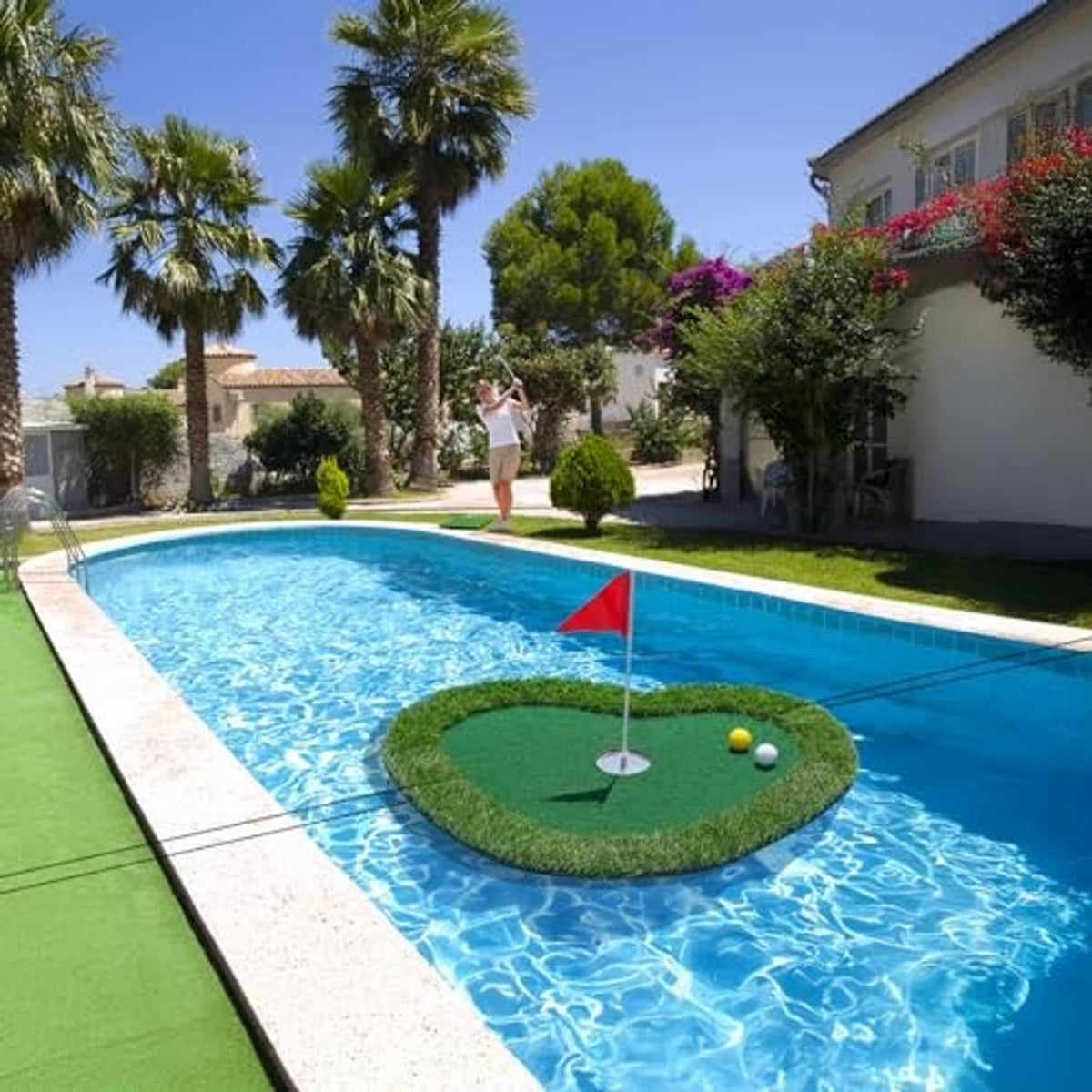 Floating golf green mat with red flag and golf balls on pool surface