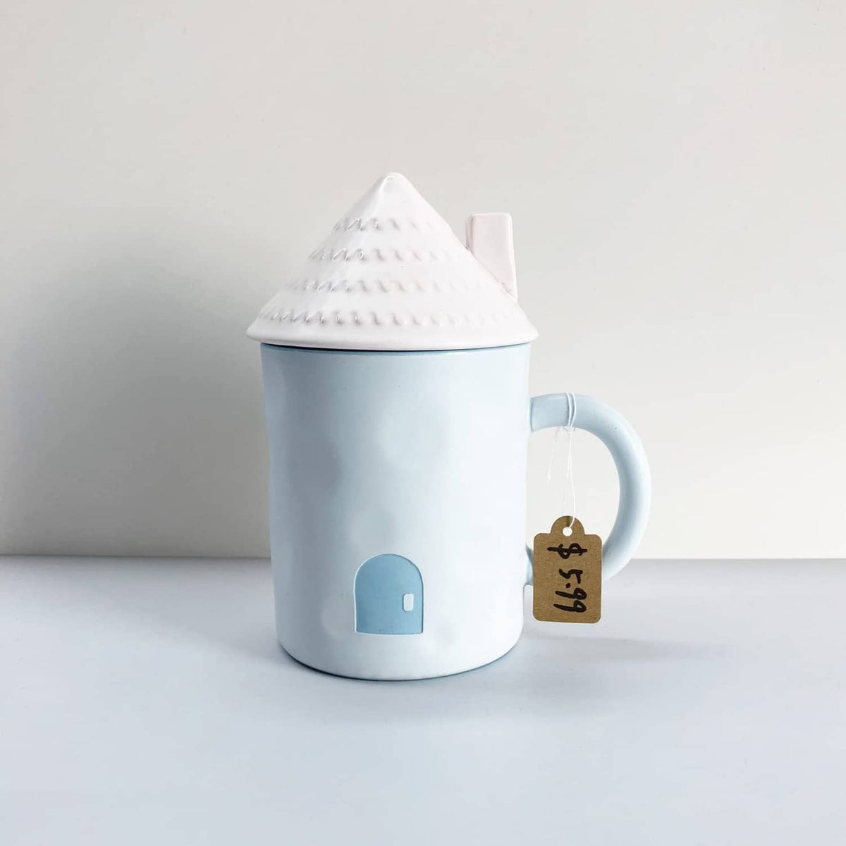 Kraft paper hang tag on string attached to a light blue ceramic canister
