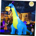 Inflatable blue dinosaur Halloween decoration with green stripe, purple hat, holding pumpkin