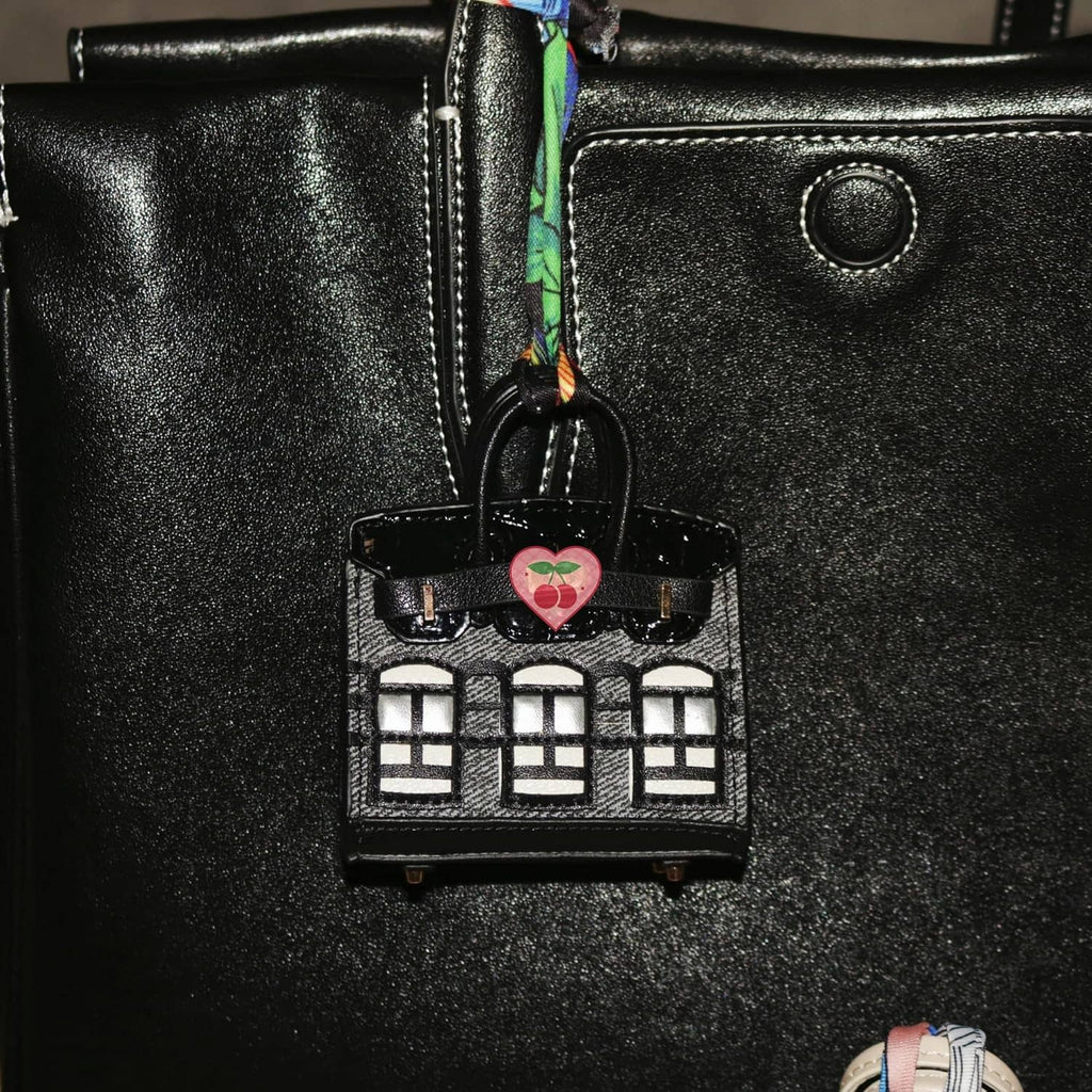 Black mini backpack keychain pouch close-up with heart charm and window detail.