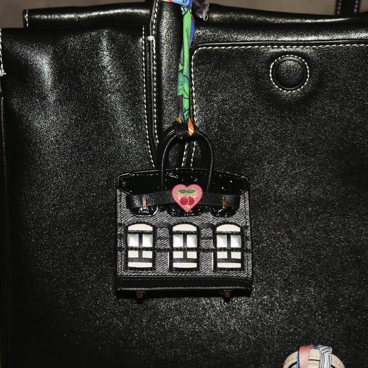 Black mini backpack keychain pouch close-up with heart charm and window detail.