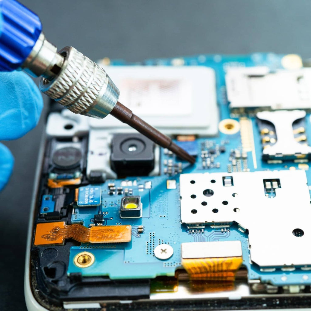 Phillips screwdriver bit tip touching a screw on a blue circuit board device