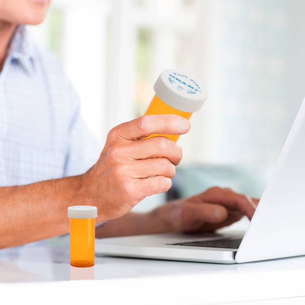 Orange plastic pill bottle with white push-down cap held by hand