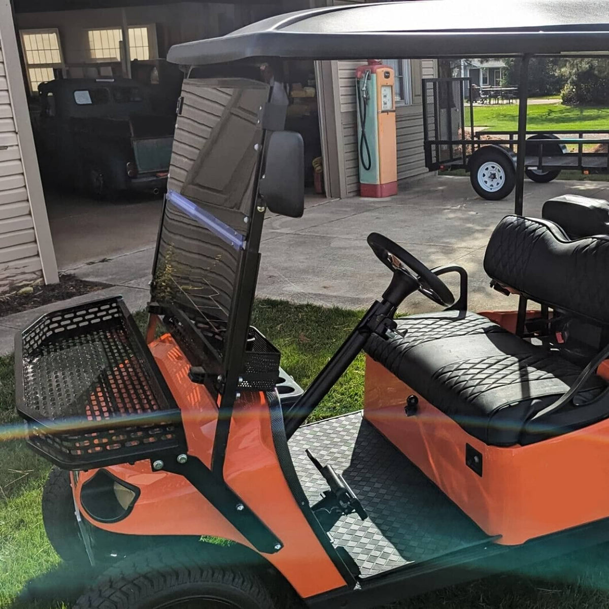 Side view of tinted fold-down windshield on golf cart with black frame and smoky panel.