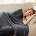Cooling blanket in dark gray with soft woven texture, draped across a bed