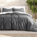 Queen duvet cover set in dark gray, with matching pillow shams on bed.