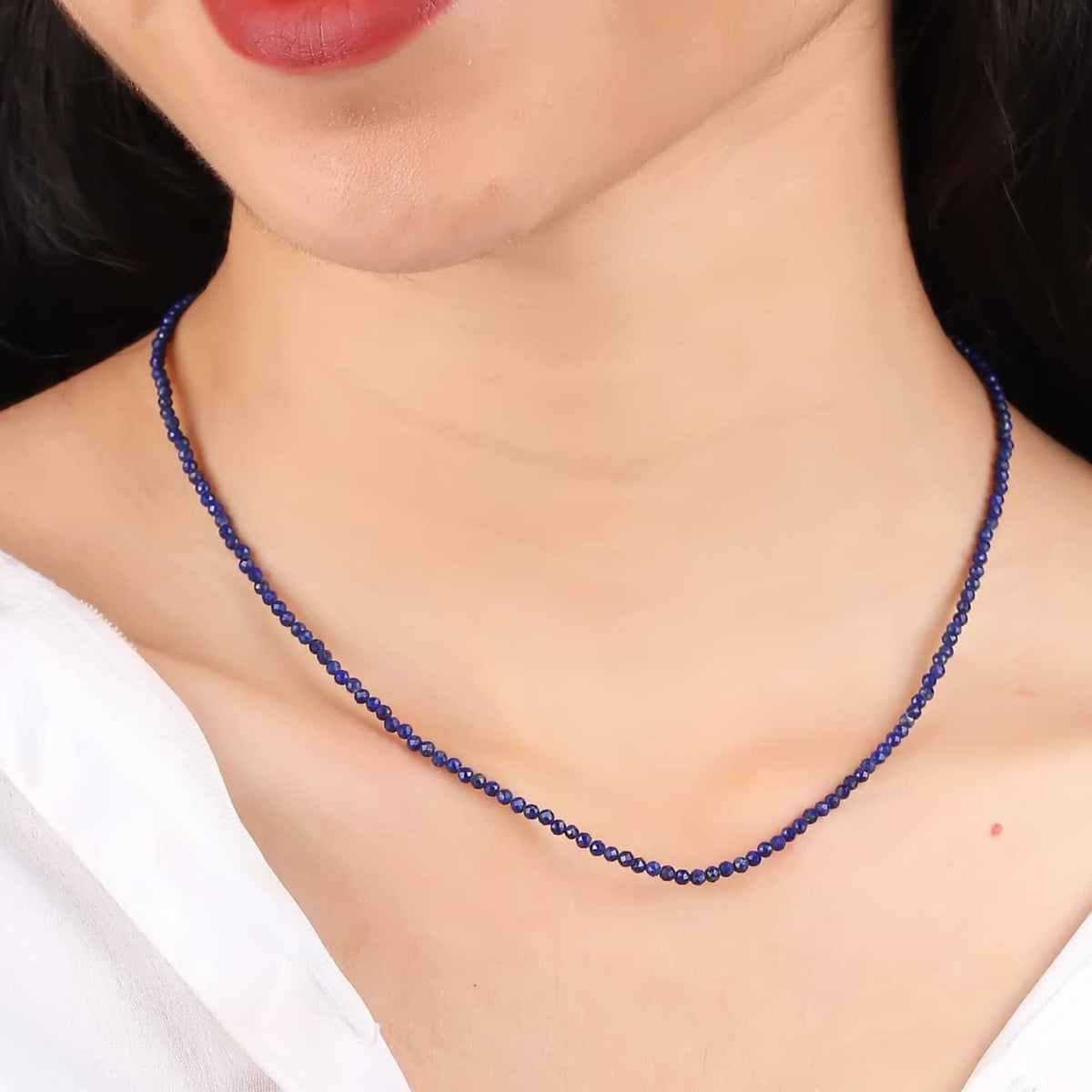 Lapis lazuli beaded necklace worn close-up, dark blue bead strand at neckline