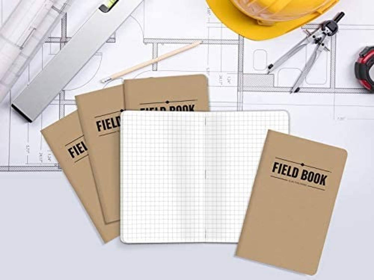 Five kraft pocket notebooks with 'FIELD BOOK' covers on a blueprint with grid paper