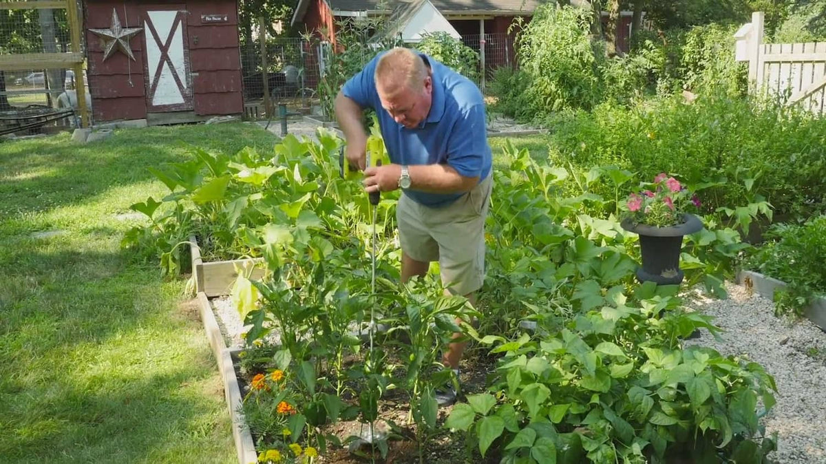 Handheld drill tiller attachment used in a backyard vegetable garden bed