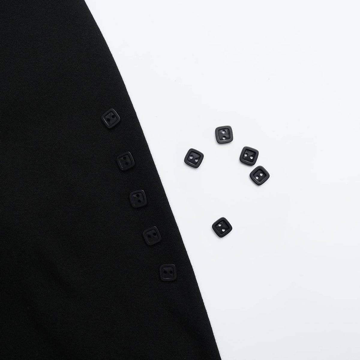 Black square 2-hole resin buttons on a dark-and-white garment panel