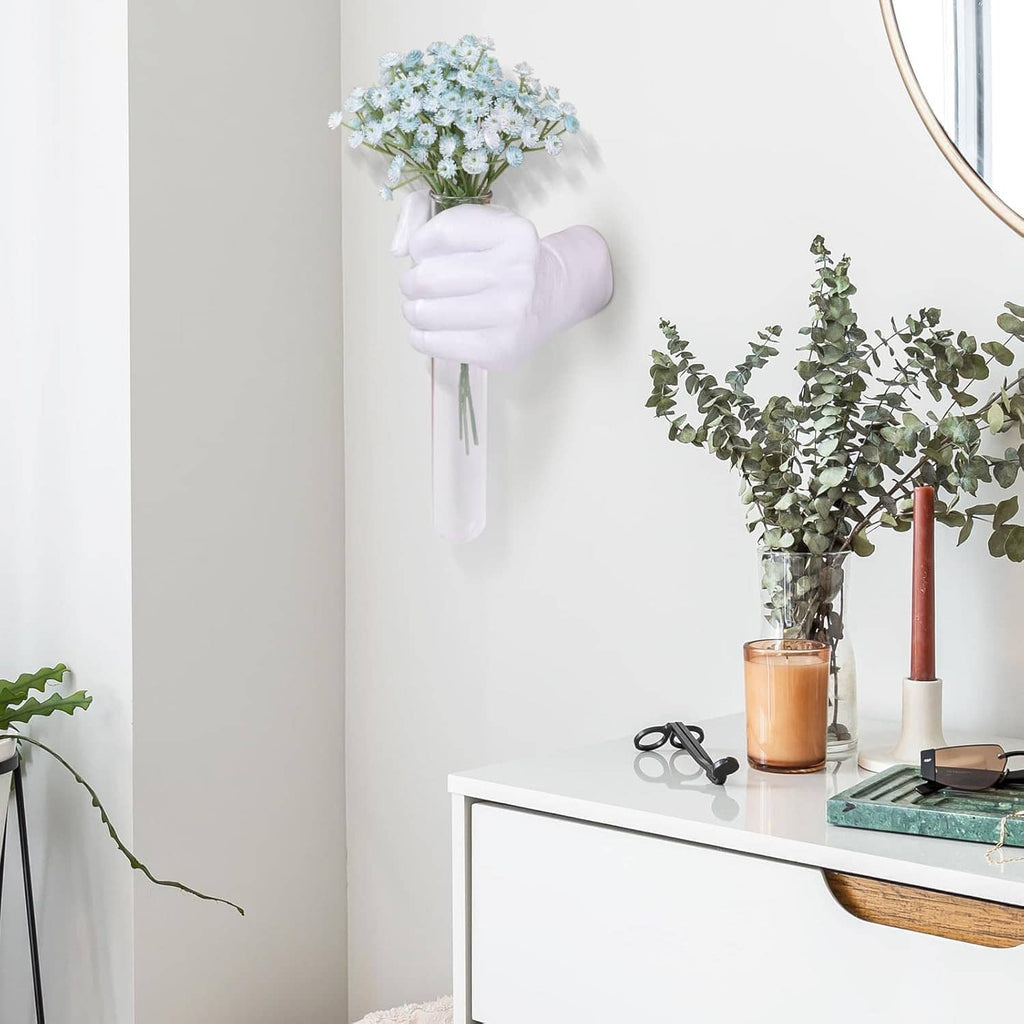 White hand vase wall hanging holding a small blue-white flower bouquet